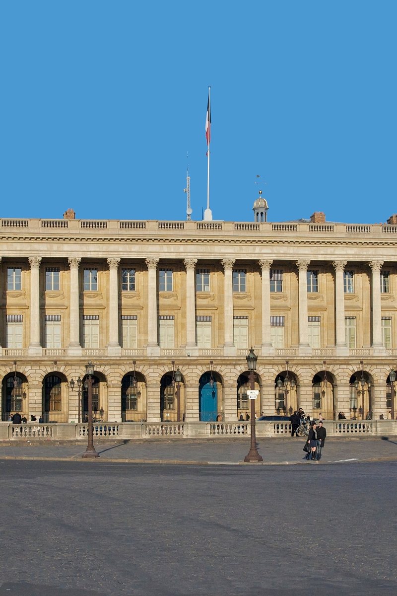 La facciata colonnata dell'Hôtel de la Marine su Place de la Concorde a Parigi — un lungo peristilio neoclassico di colonne corinzie binate sopra un porticato in pietra, che risplende nella luce del tardo pomeriggio. Parigi, Francia.